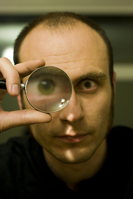 man looking through magnifying glass